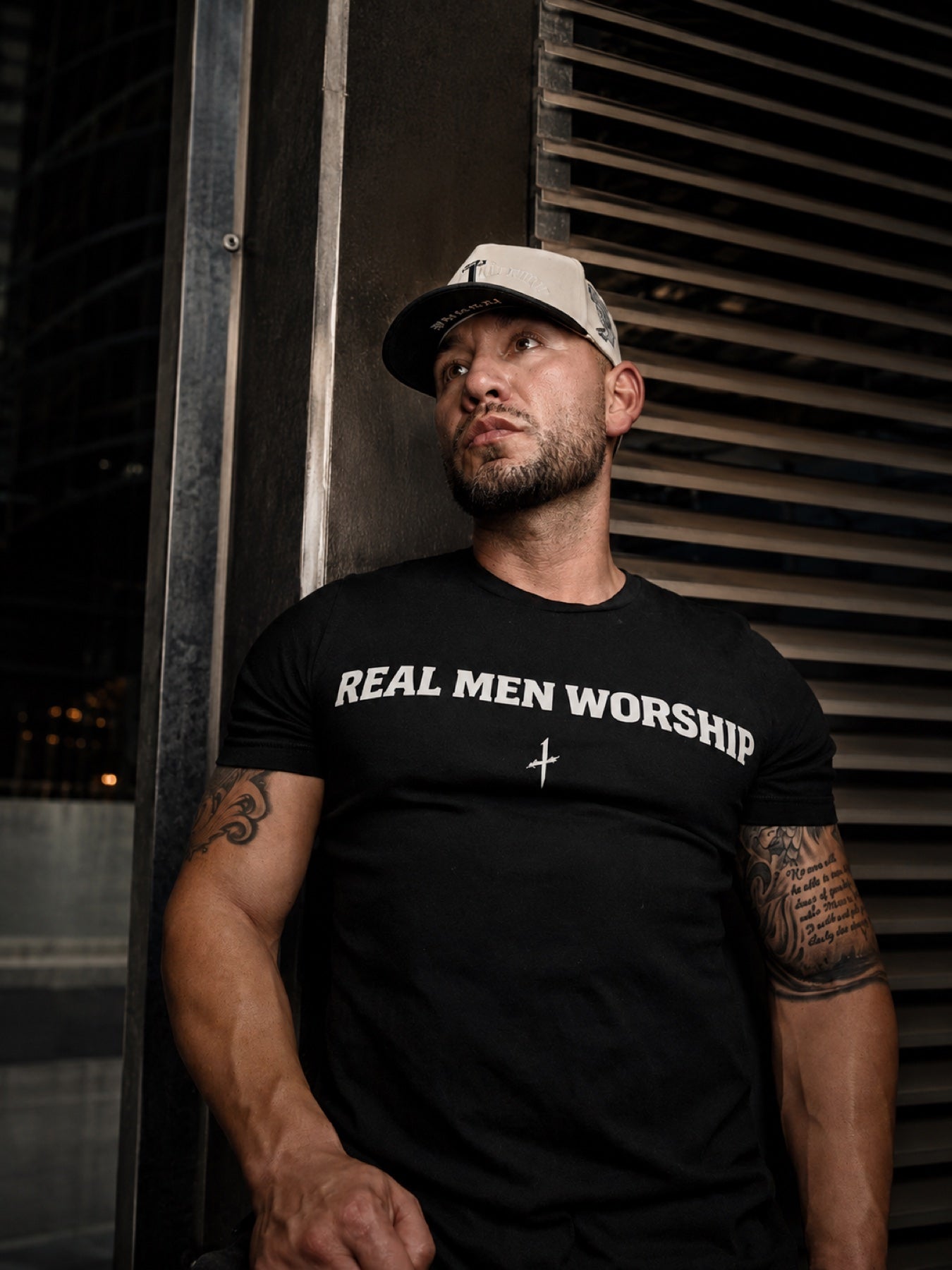 Man wearing a black Real Men Worship Christian T-shirt and Only1Crown hat